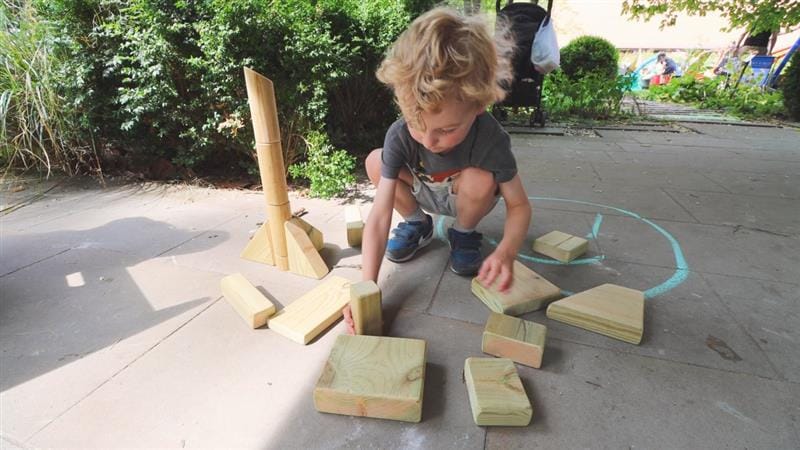 a child kneels on the floor with blocks in front of him and counts the blocks