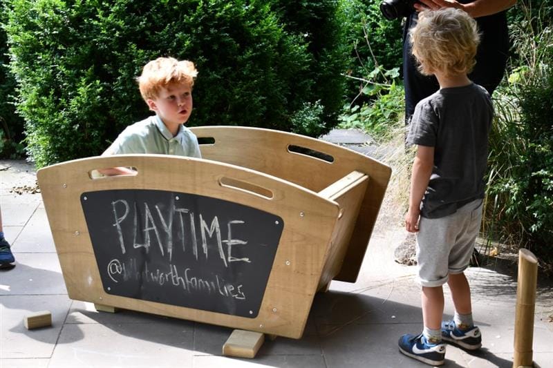 two children discuss in front of the skips