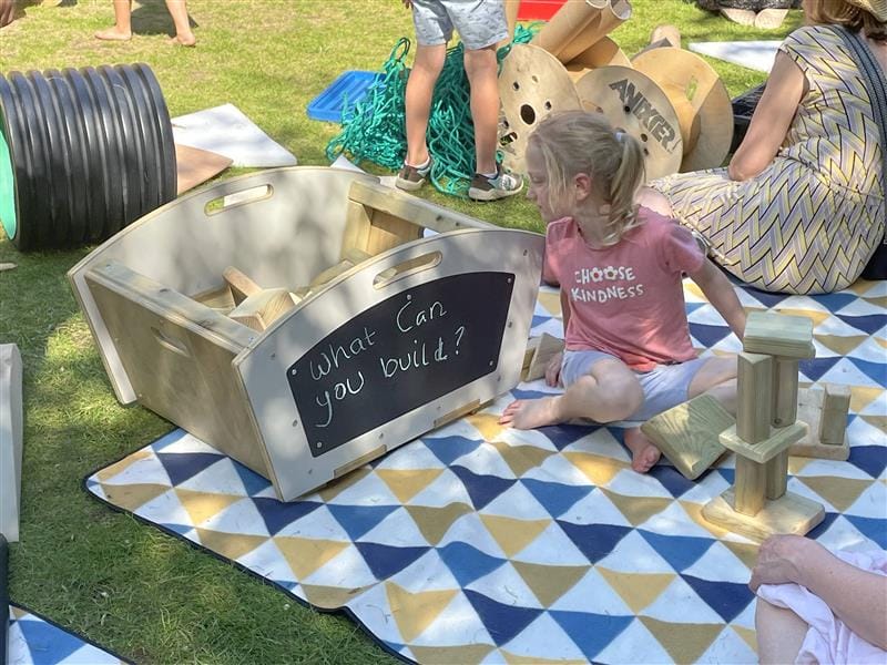 a child sits on a mat and plays with building blocks from the skip