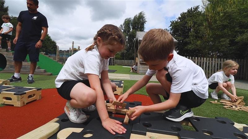 two young children playing with small blocks on top of big blocks