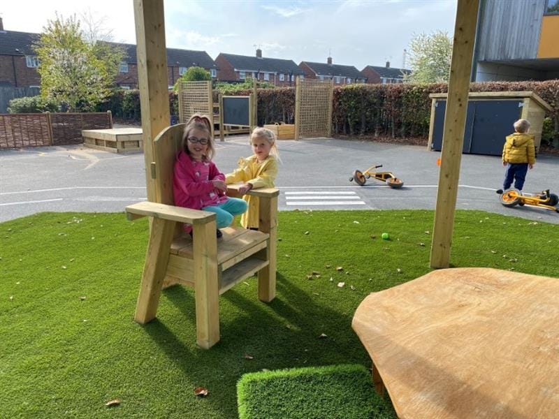two little girls stand and sit in the freestanding storytelling chair