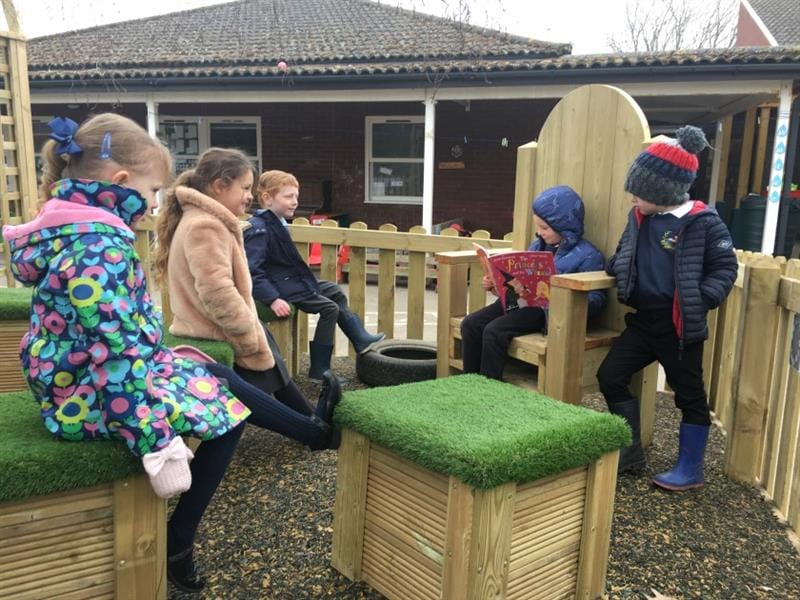 children sit and read books to one another in the reading space