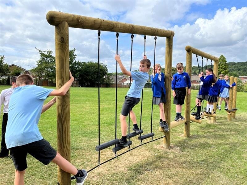 children climb along the climbing poles on the trim trail