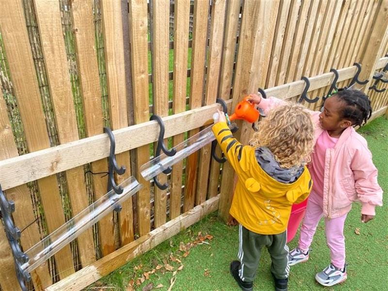 two children stand at the water channel hooks and direct water down the channels
