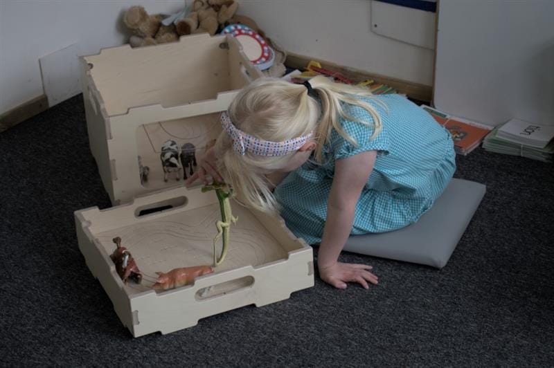 a little girl sits and plays with the resources on the top of the game top lid