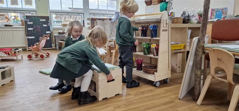 children stand in front of the art easel with the front panel removed showing the hidden storage inside