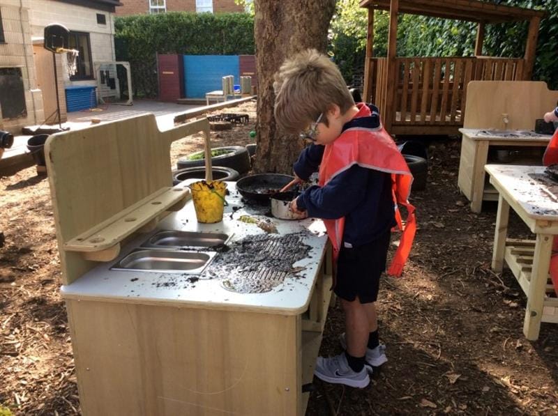 a little boy stands and looks down at the mixing bowl
