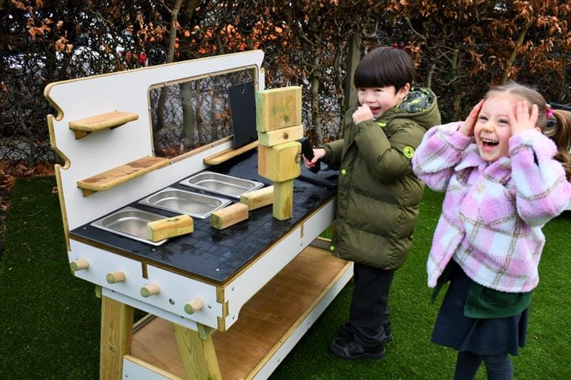 a little girl and a little boy stand and look amazed at the tower of blocks they just built 