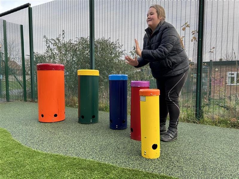 A young girl in the sen playground playing the metal drums