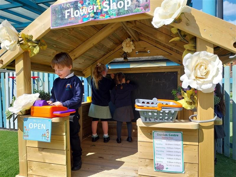 children stand inside the playhouse and pretend to work in a flower shop