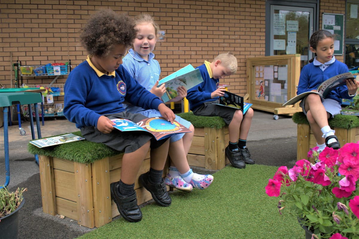 A group of four children are sat on Get Set Go Blocks and are reading different books.