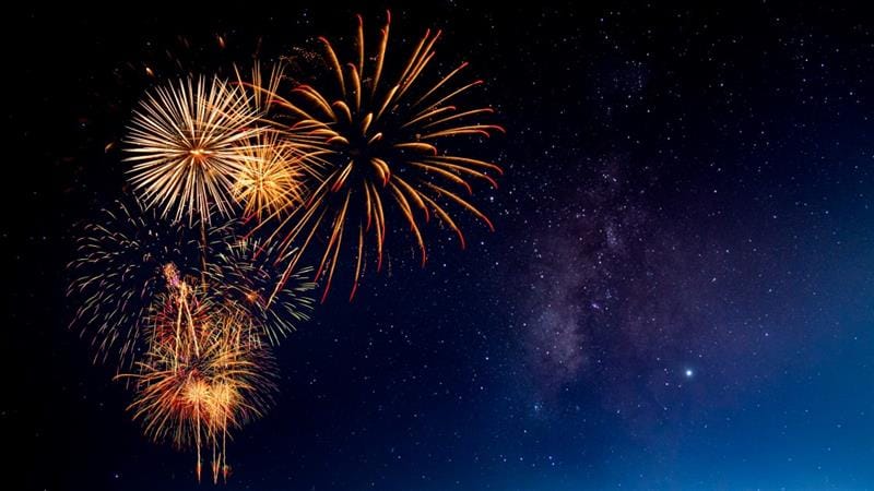 three orange fireworks in the night sky