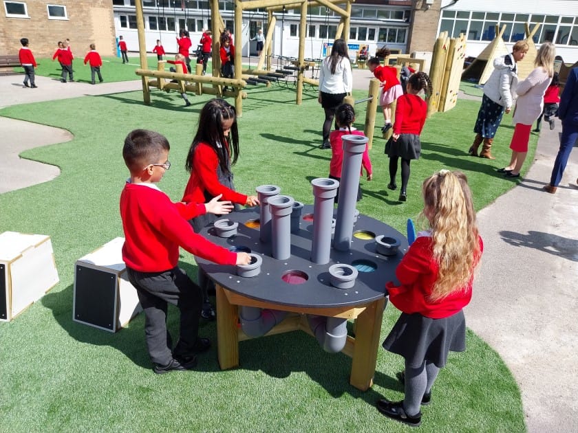 A small group of children are playing with a group batonka and are talking to each other.