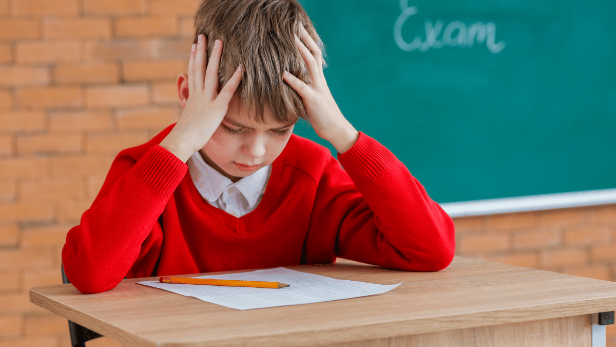 Child sat a table looking stressed about exams