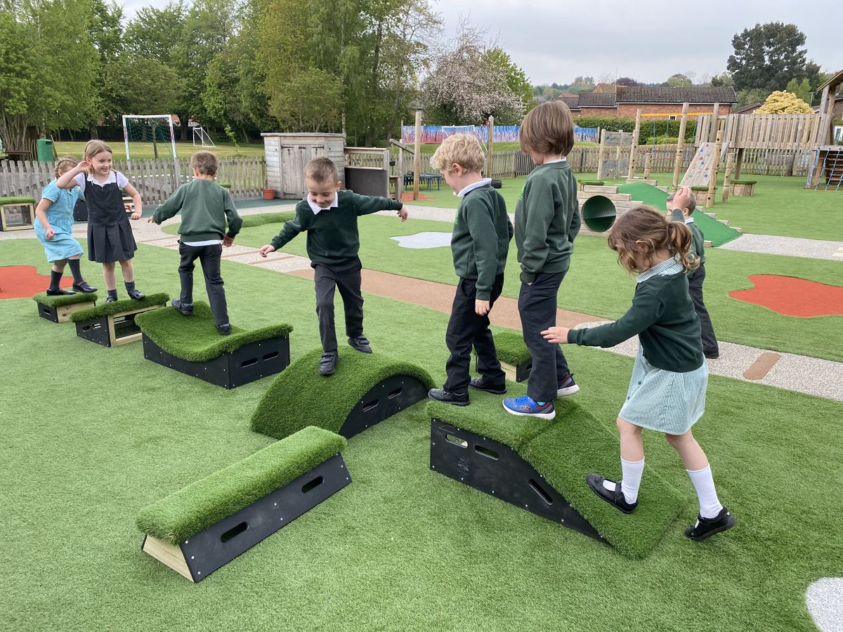A line of children are all walking across a Get Set, Go! Blocks obstacle course. The children are tackling different blocks as they pose and have fun on the equipment.