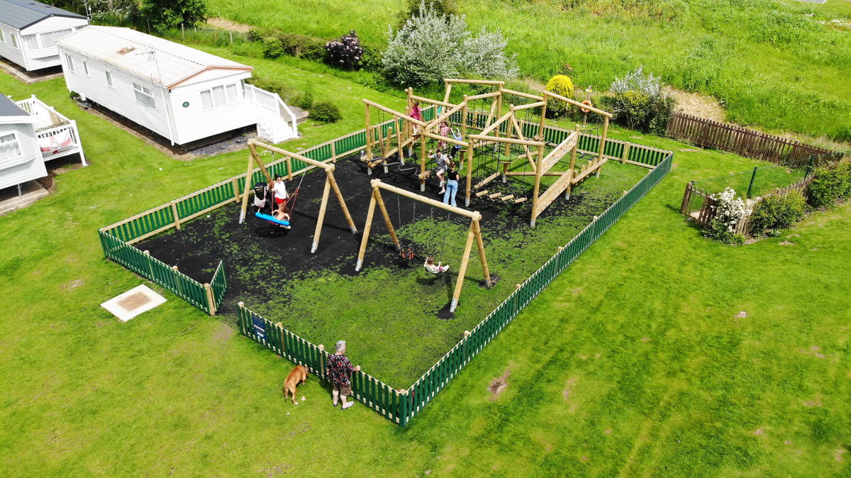 A large playground with safermats surfacing, swings and a forest circuit, located next to a caravan park.