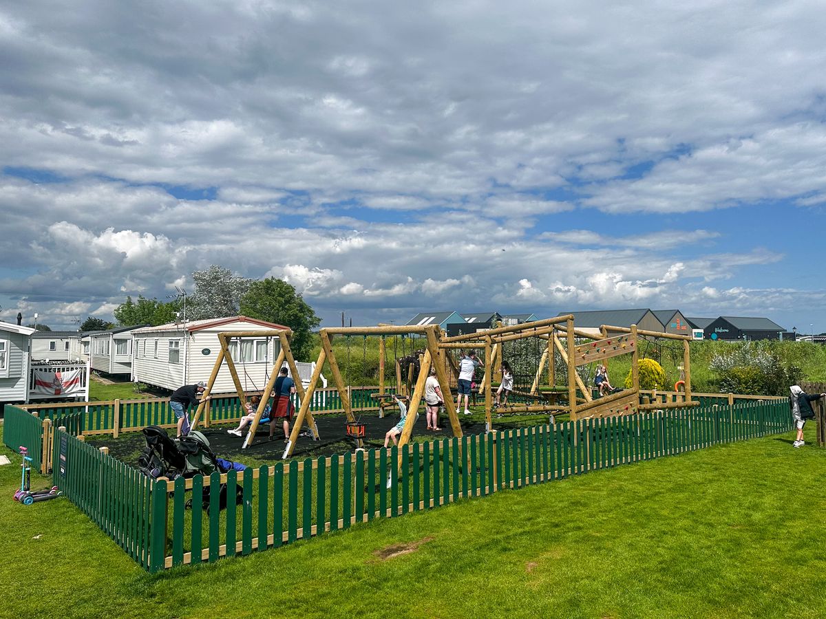A commercial playground installed at a caravan park with grass mats for the surfacing.