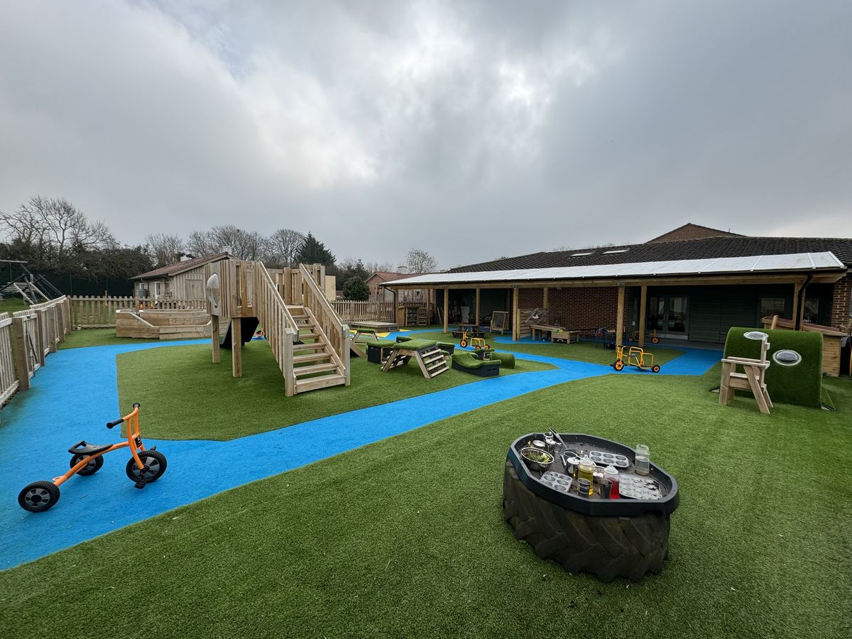 An empty artificial grass playground that has a few large wooden structures on it.