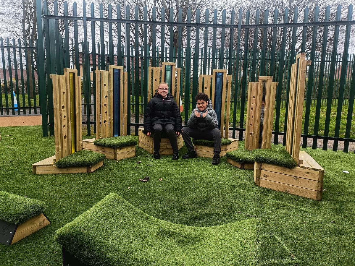 Two children are sat on the Sensory Seating Circle as they look at the camera and smile.