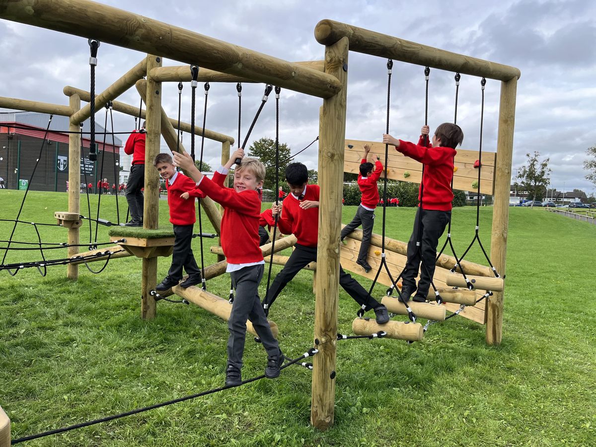 A group of children are making their way around a Forest Circuit that has been installed on natural grass.