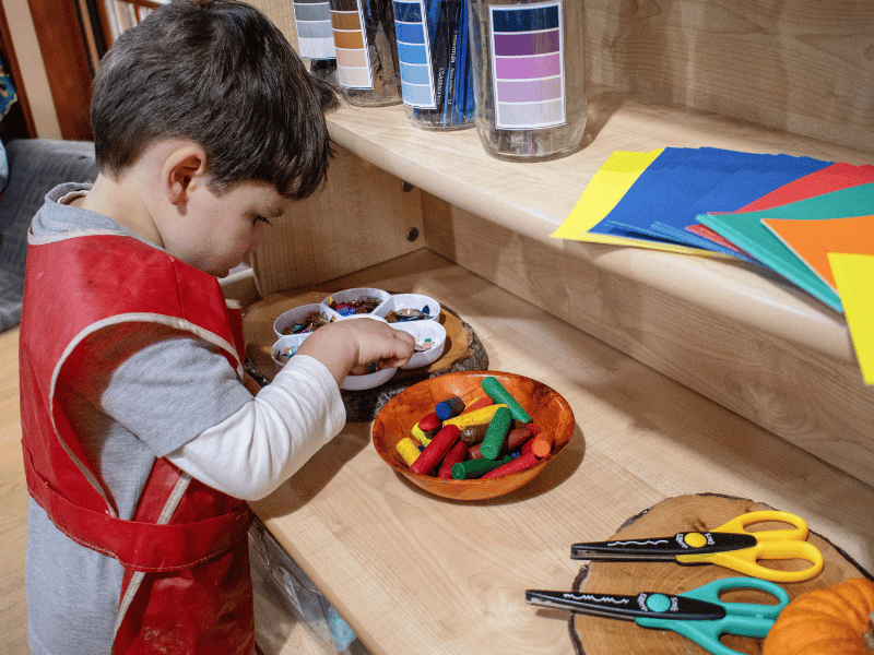 A little boy is looking through a variety of arts and crafts decorations on a Millhouse Welsh Dresser.