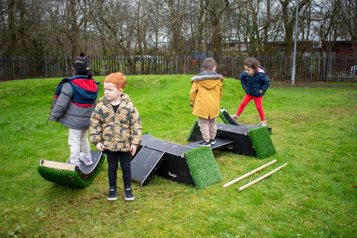 A group of children are playing on the Rockies, exploring various elements to improve their physical development.