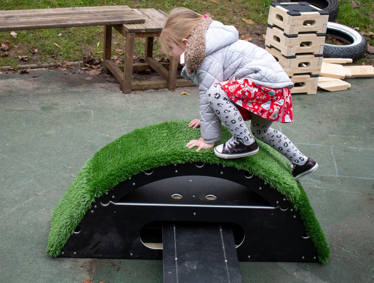 A little girl is climbing over the ramped block that is included in the Rockies.