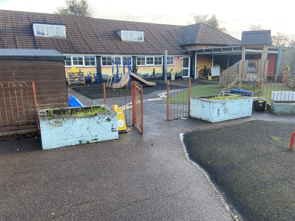 An old playground that has poor drainage, with rain pooling around the edeges of the surfacing.