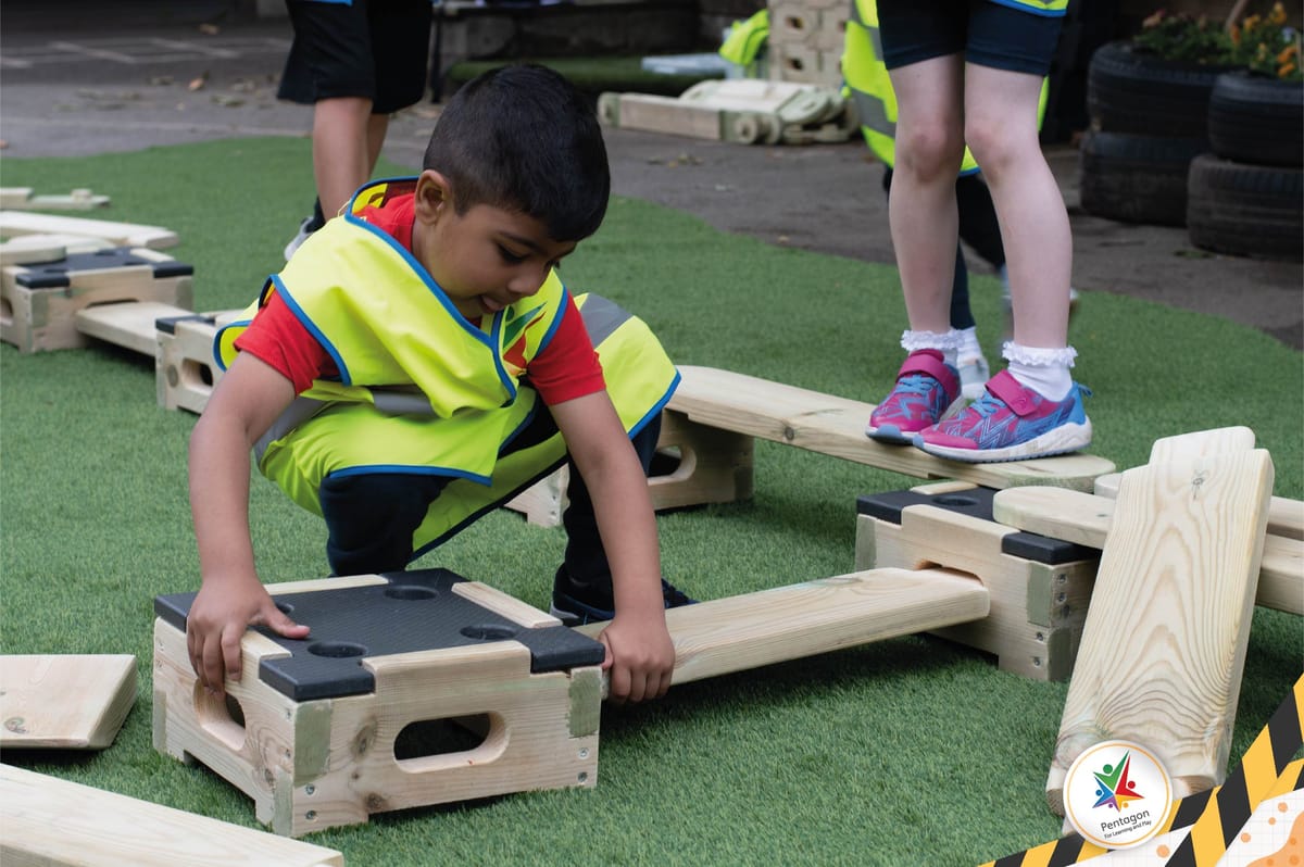 A boy is placing a Play Builder plank on a Play Builder block.
