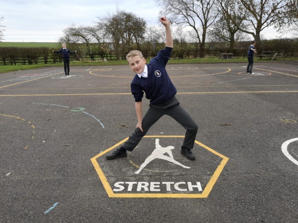 A boy is stretching on a thermoplastic graphic and is looking at the camera.