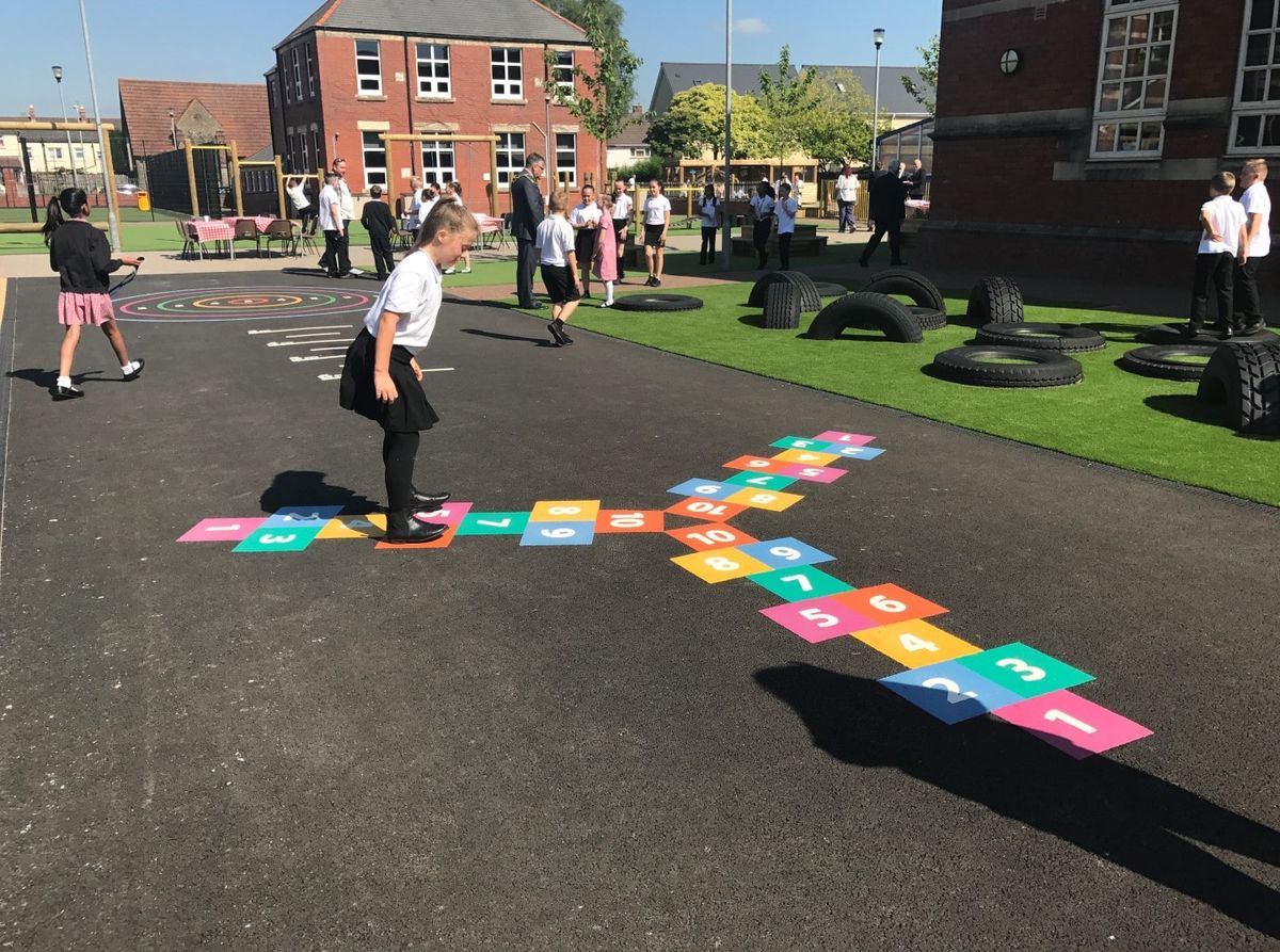 A little girl is playing on a three-way hopscotch playground graphic.