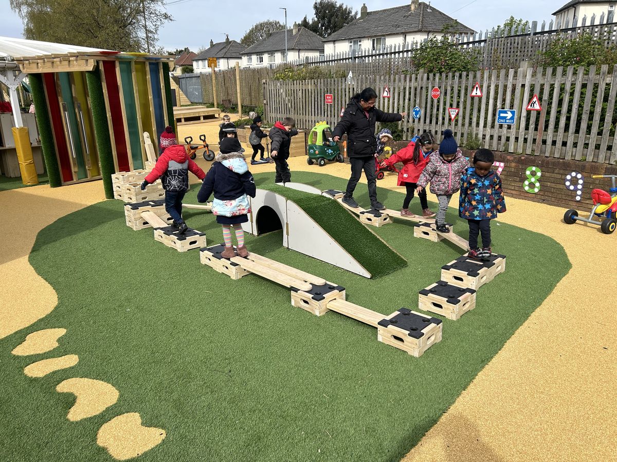A group of EYFS children are playing on a Play Builder set, which has been set up to create an activity circuit.