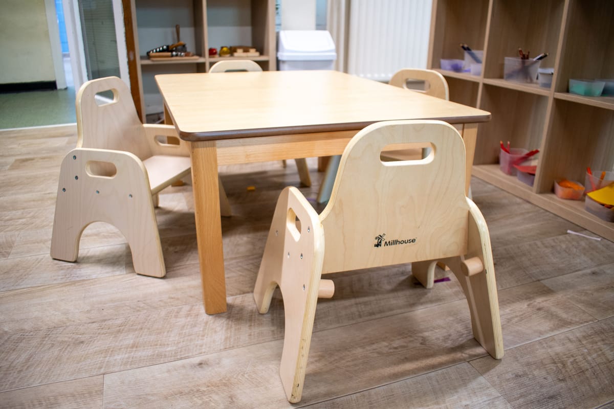 A small wooden table and five chairs are placed together to create a more cohesive environment.