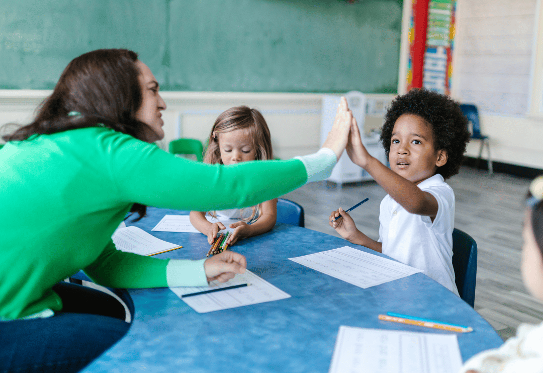 An EYFS teacher is giving one of her students a hi-five