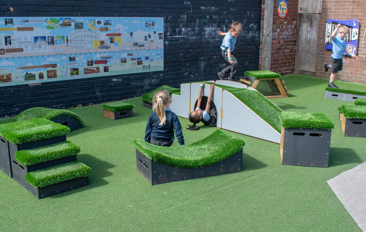 Different Get Set Go blocks are surrounding the Up and Under Ramp and Stair set, with children exploring the new play equipment.