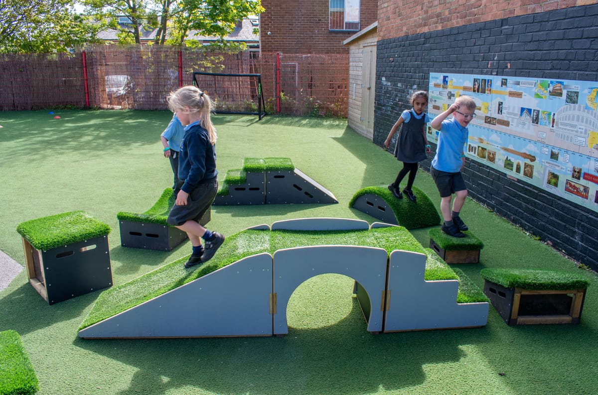 Four children are playing on an obstacle course that has been created from Get Set Go Blocks and the Up and Under set