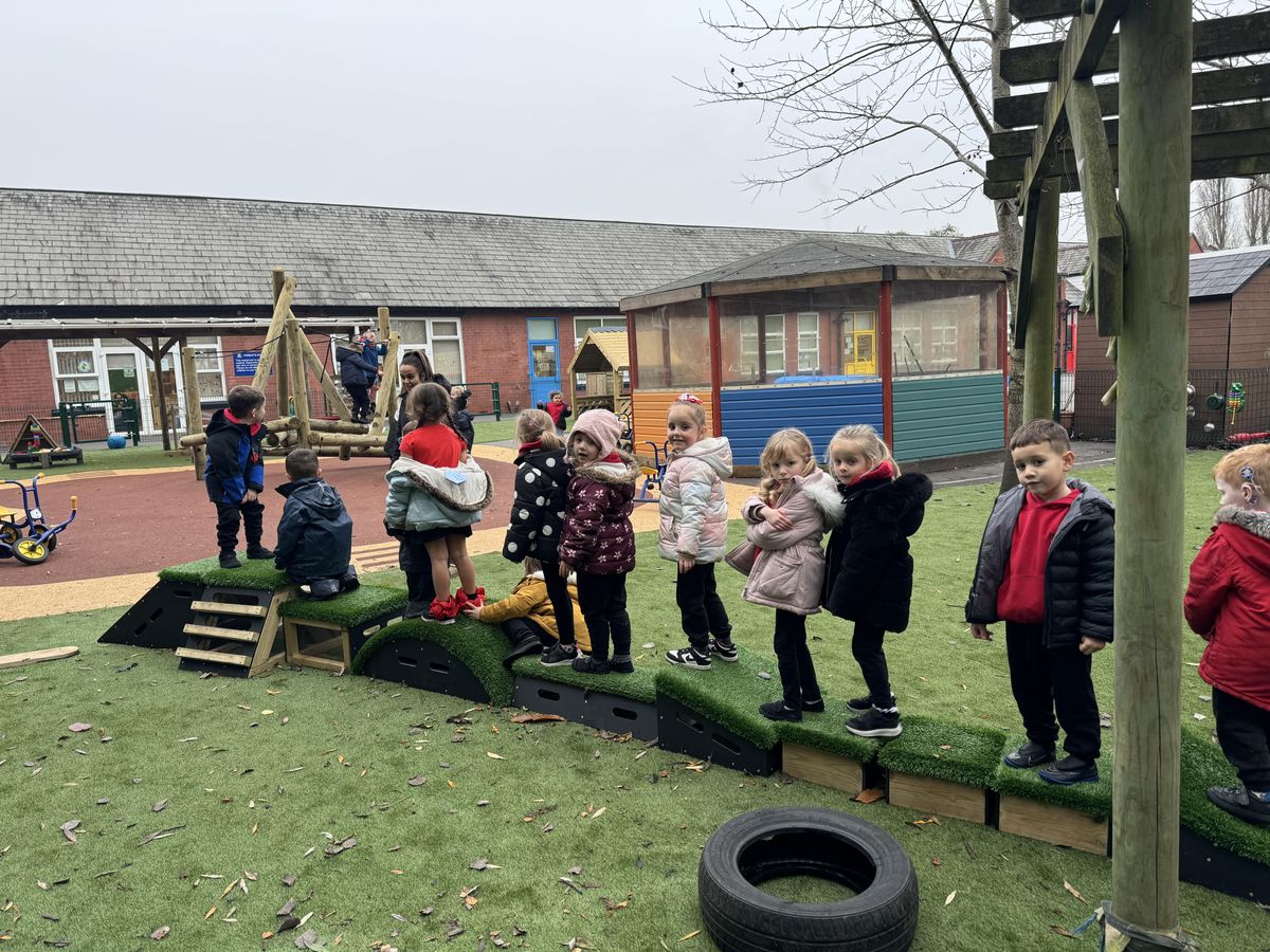 A long line of EYFS children are stood on different Get Set Go blocks as they all look at the camera and smile.