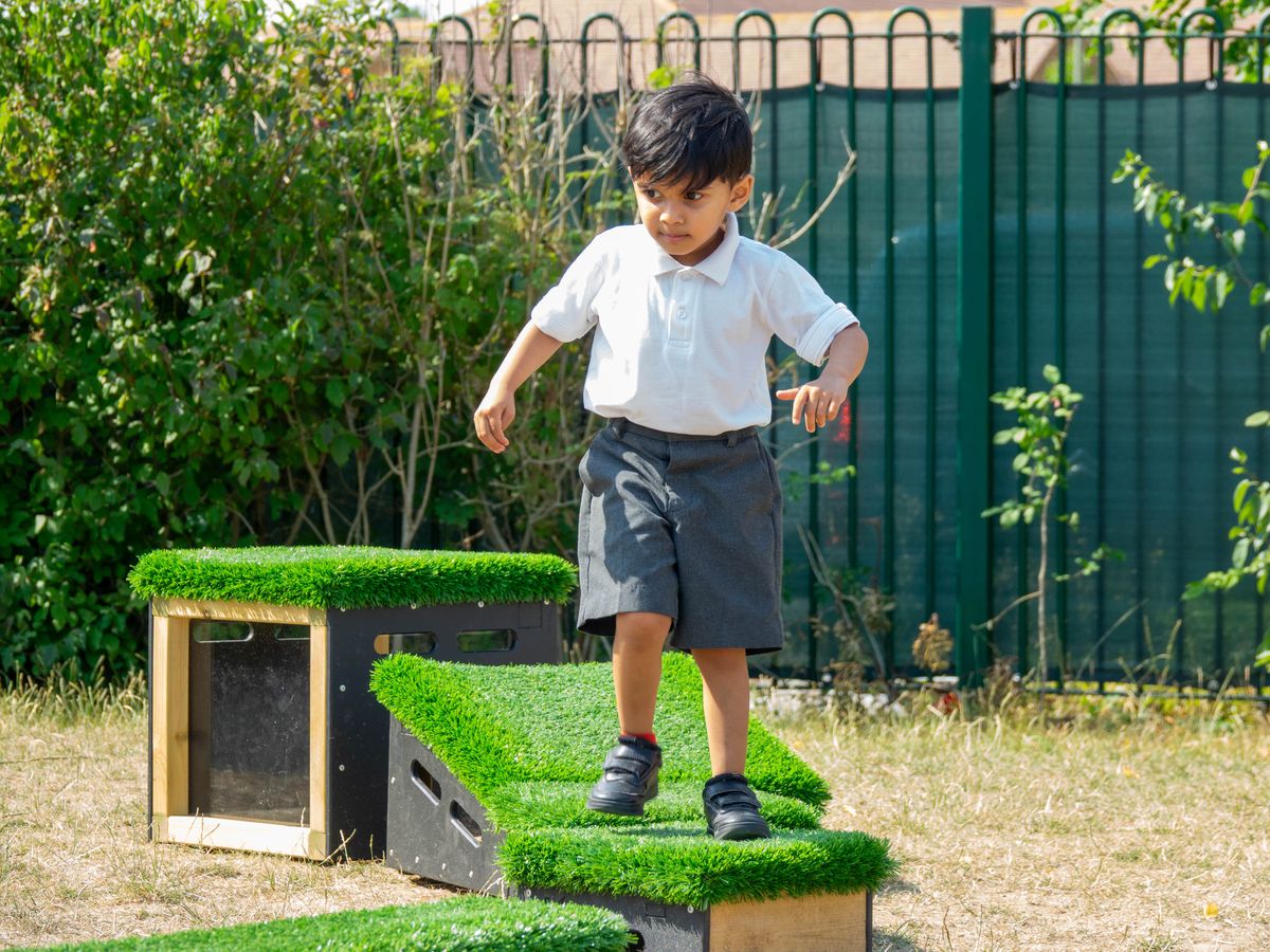 A little boy is walking across a set of Get Set Go blocks, heading towards the camera.