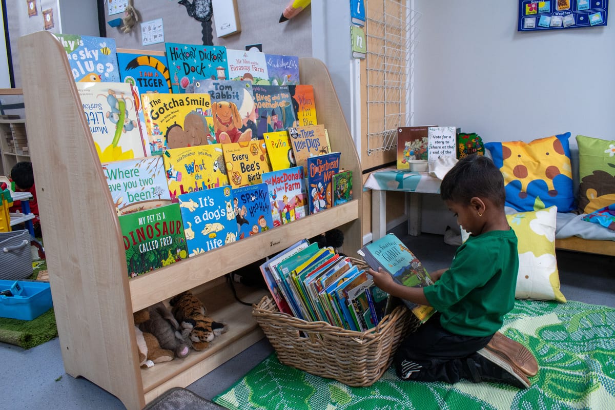 A little boy is holding a book up to his face, as he selects a new book to read.