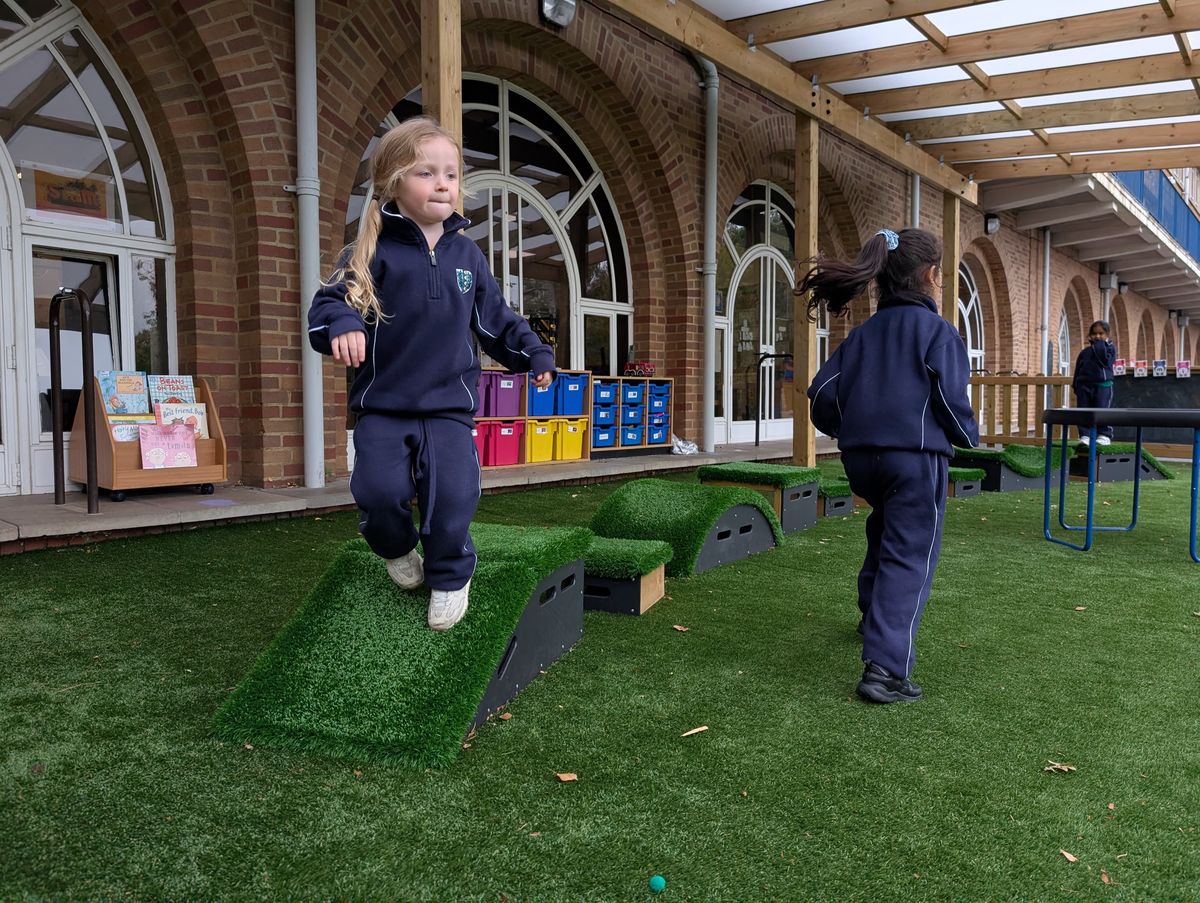 A little girl is walking down the ramp block from the Get Set Go Blocks set, as another child walks past her to get to the beginning of the course.
