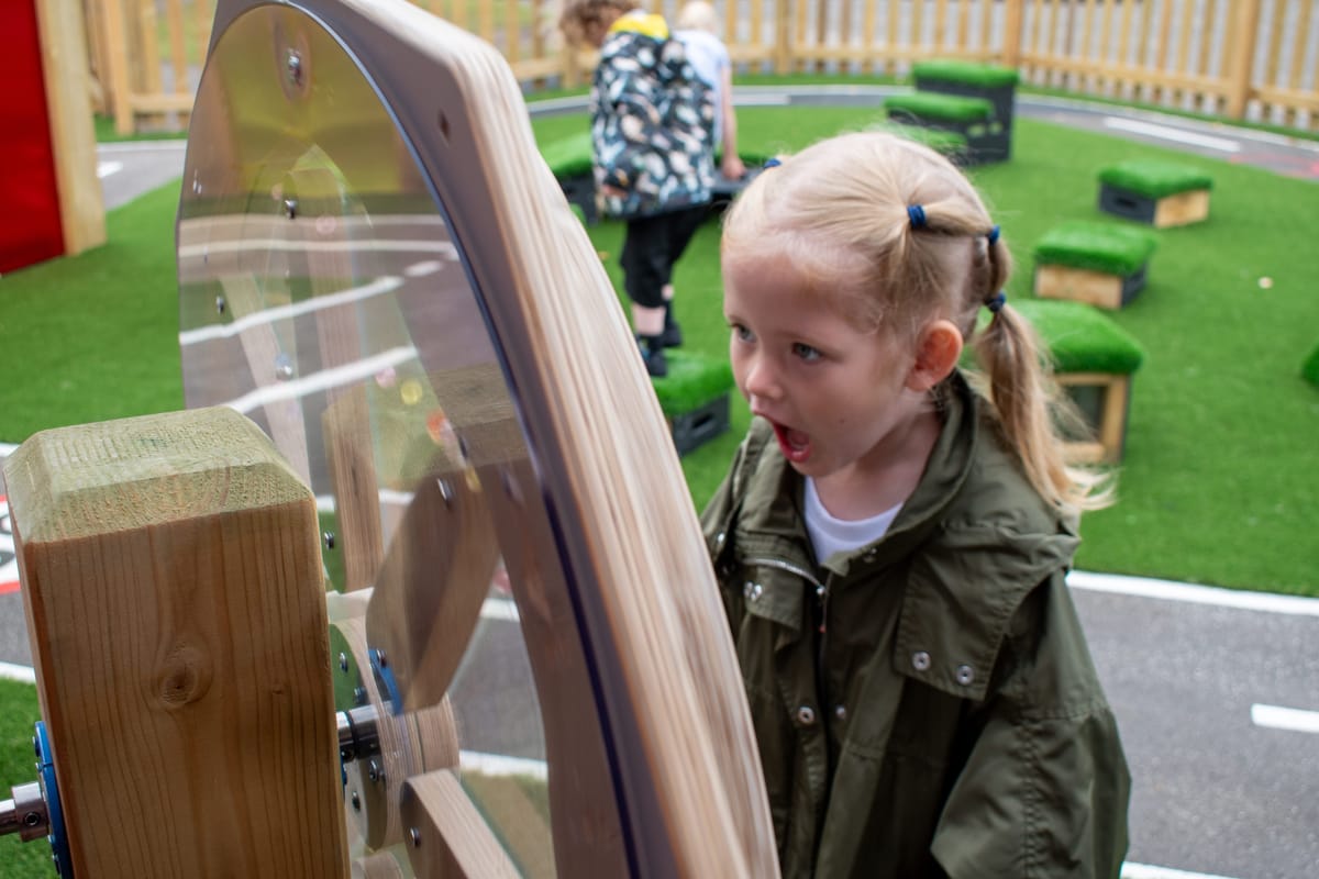 A girl is looking amazed at a sensory spinner as she plays with it.