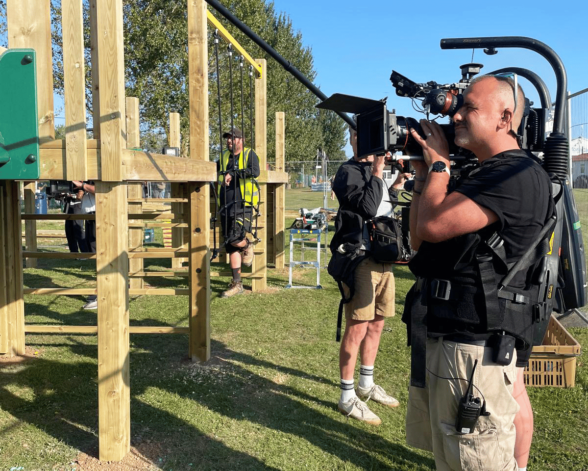 A man with a camera is filming the play equipment.
