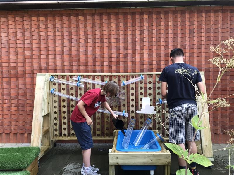 two children stand and play with the water wall