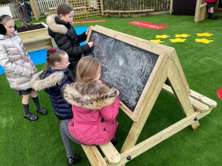 Children sat drawing on an easel table chalkboard