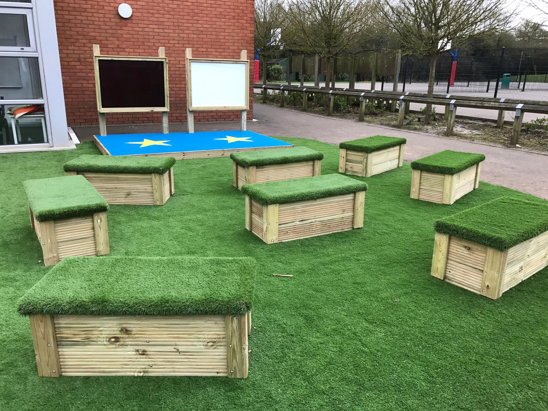 A set of large movable artificial grass-topped seats.