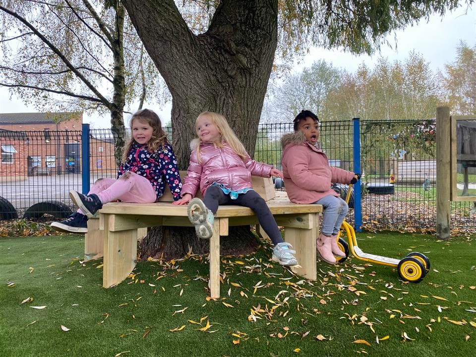 3 children playing and sitting on the tree bench.