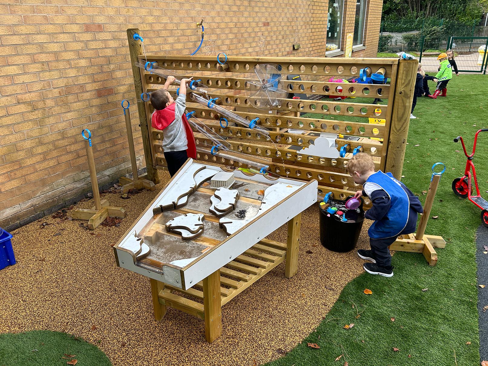 Two nursery children pouring water down the Water Wall with Damming Package