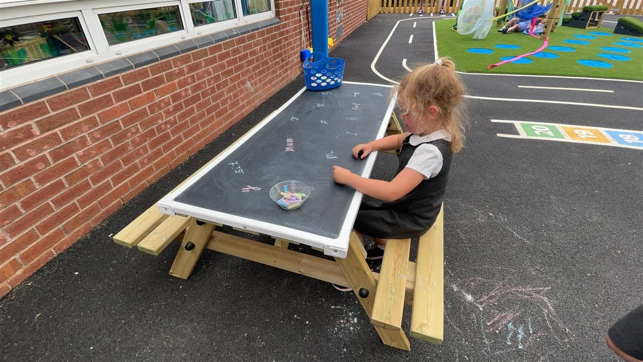 children playing on picnic table with chalkboard