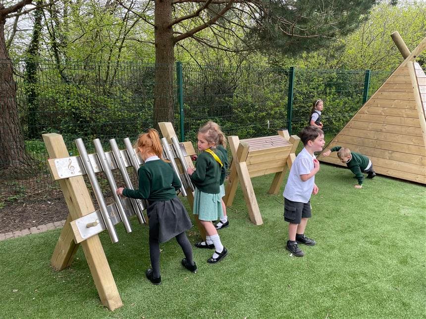 a group of young girl playing the freestanding chimes in their playground