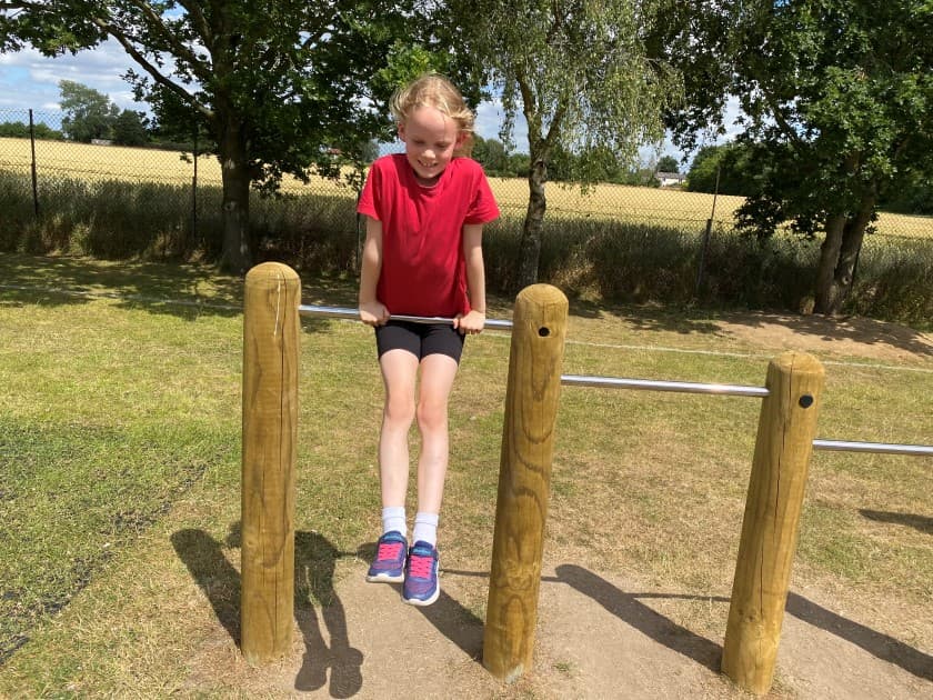 a little girl builds her upper arm strength on the rollover bars